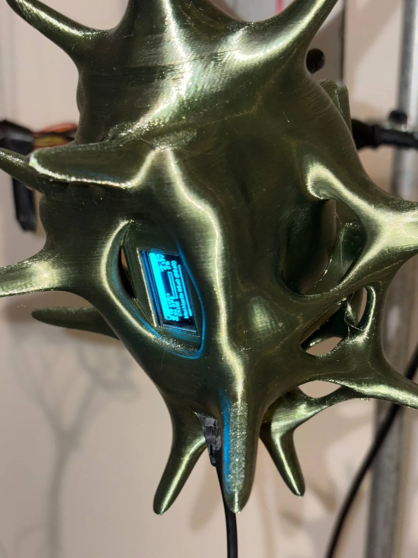 Close-up of a green spiked form with an illuminated blue display inside.