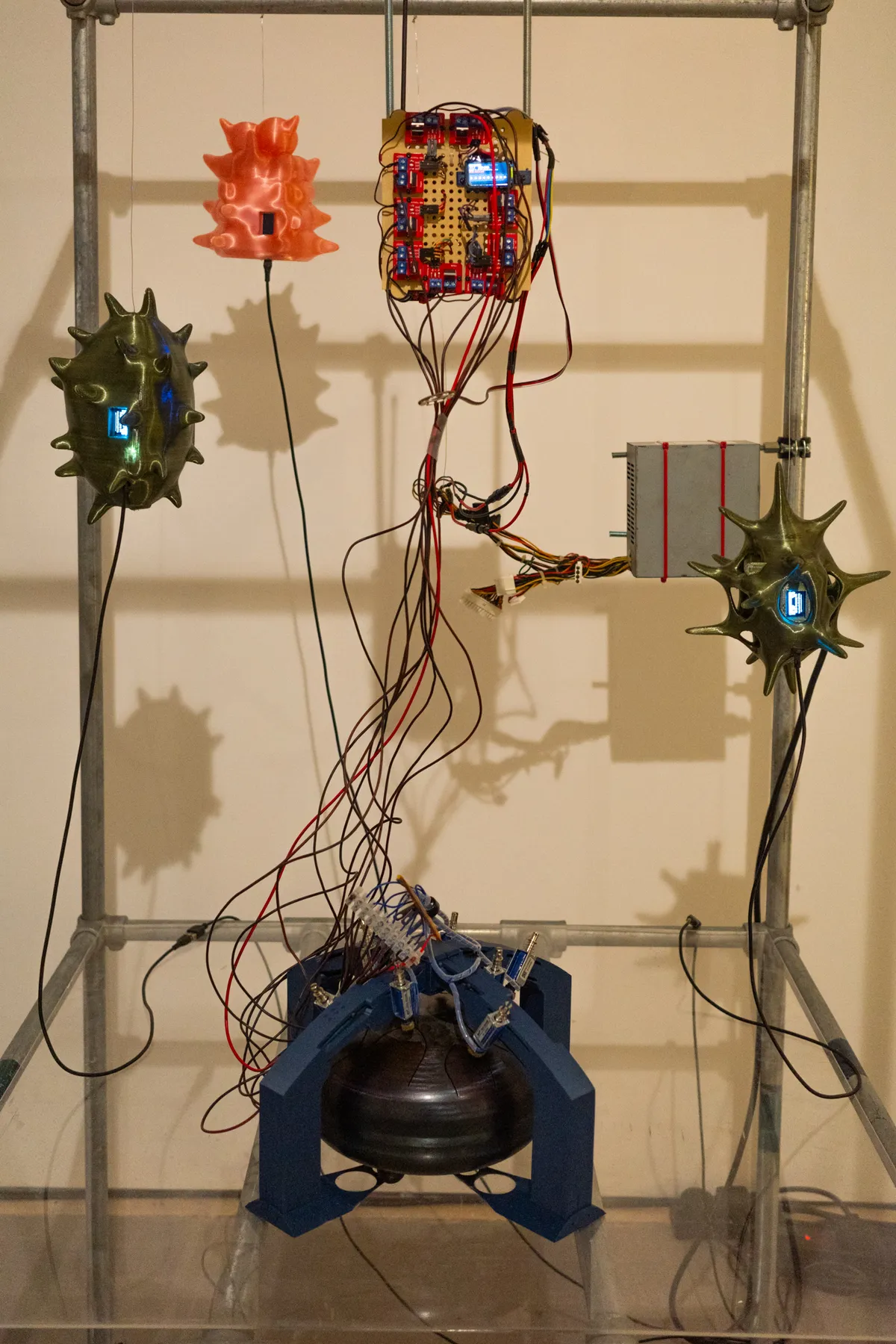 Central view of the installation showing three spiked forms, circuit board and suspended wires.